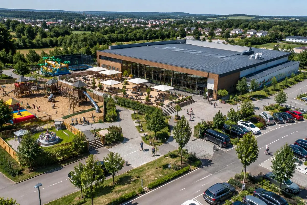 Luftaufnahme eines Freizeitstandorts mit Halle, Außenspielbereich und Café-Terrasse